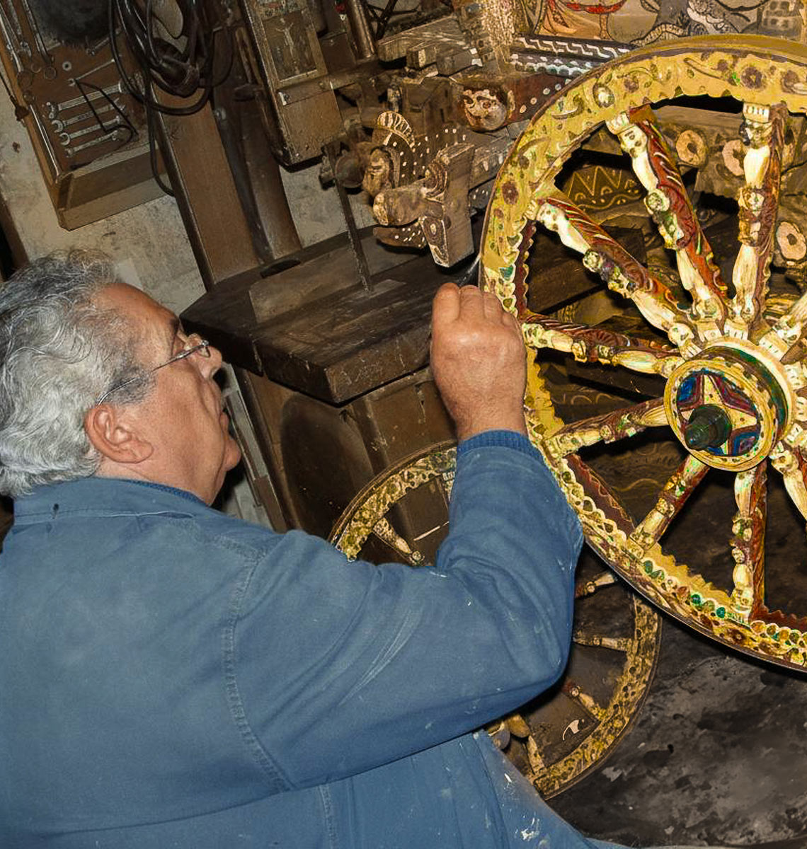Il mastro carradore Salvatore Sperandeo che decora una ruota di carretto.